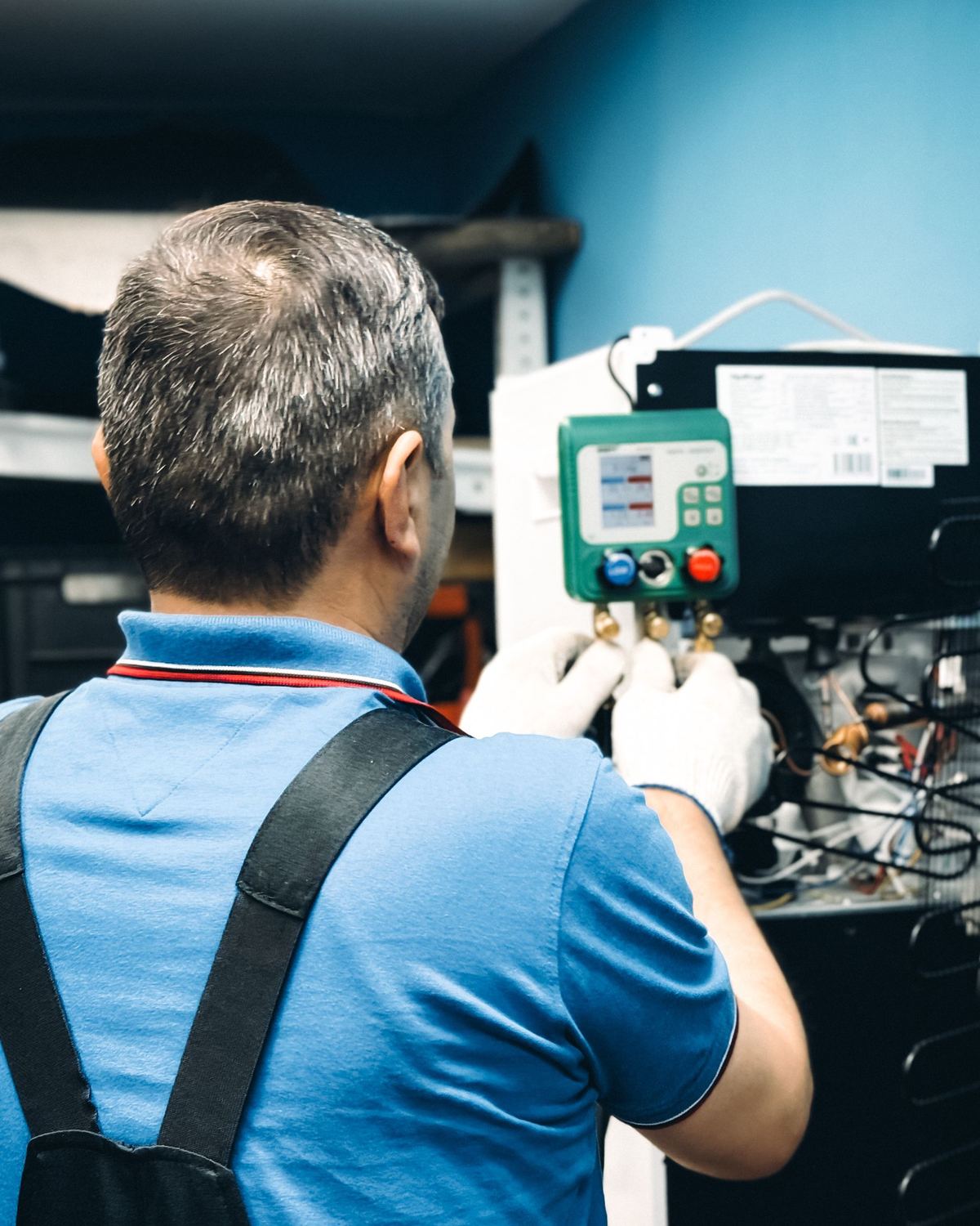 Stock photo of an HVAC technician checking refrigerant gauges